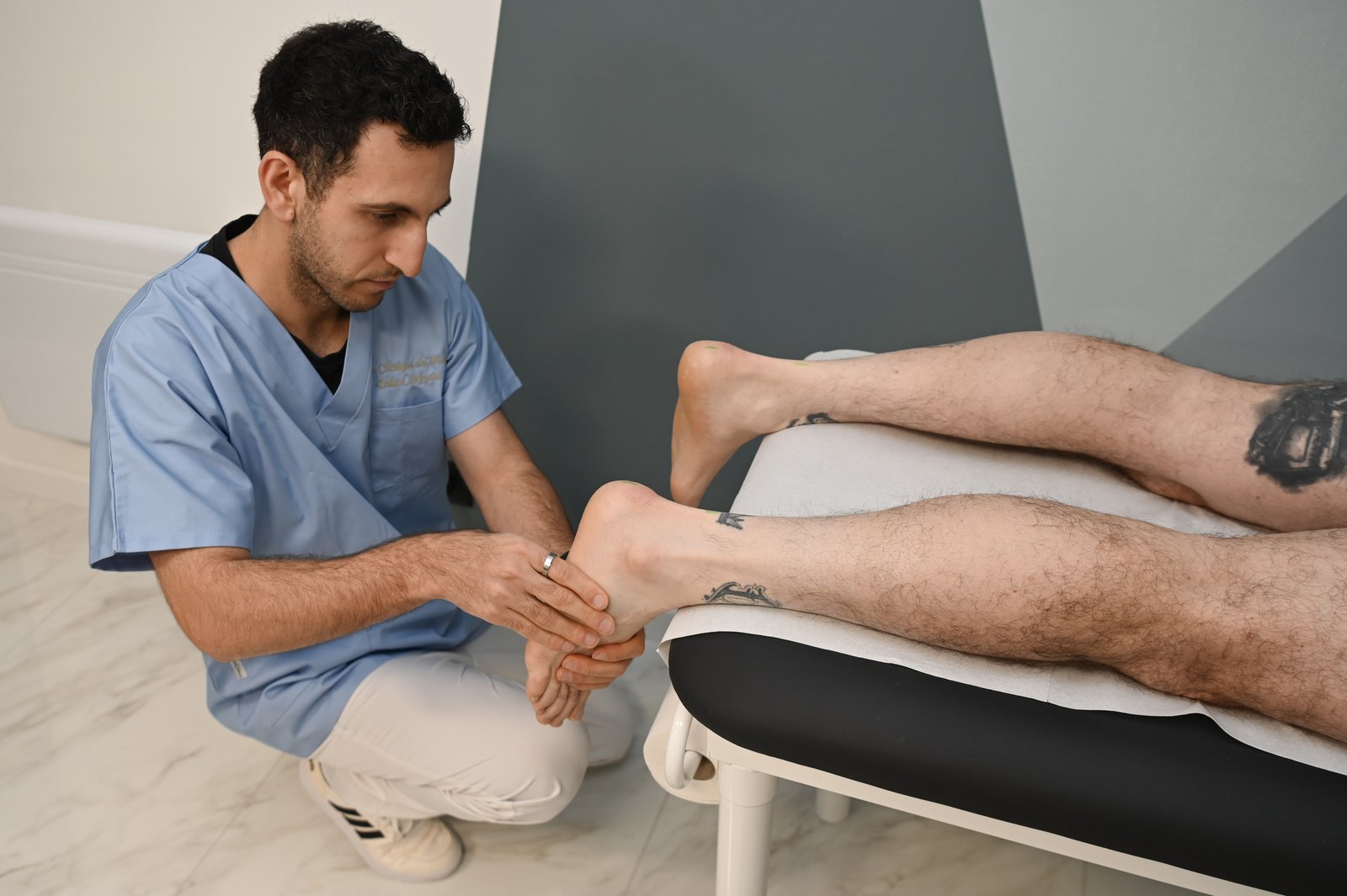 Examen clinique : le podologue examine la cheville et le pied d’un patient allongé